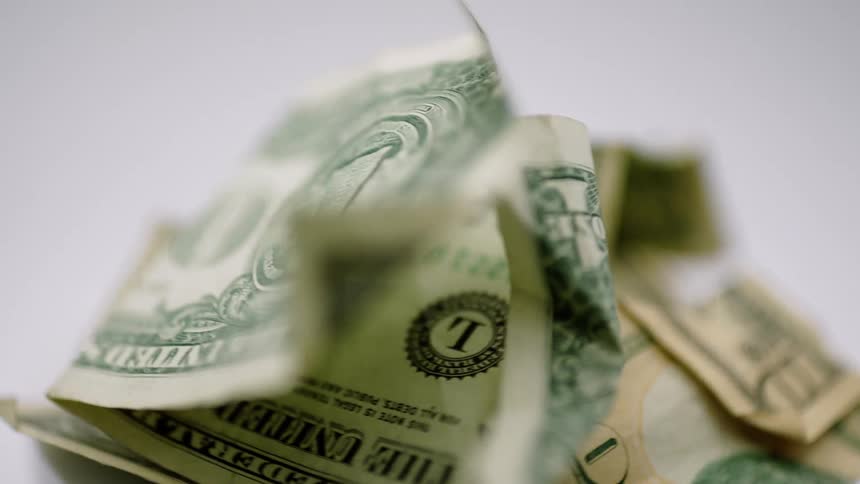 A pile of several folded crumpled american dollar bills a one and a ten are rotating
