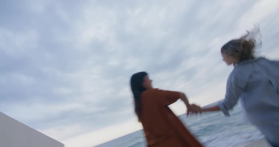 Women run through tunnel to beach and dance and hug