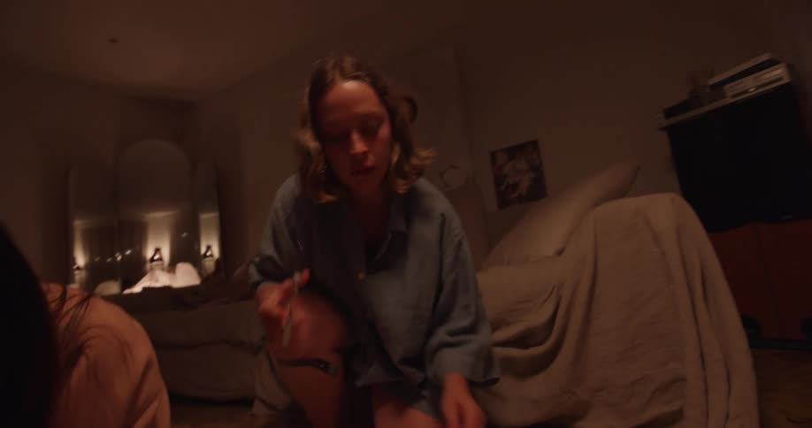Two teenage girls sit on a bedroom floor and work on a posterboard