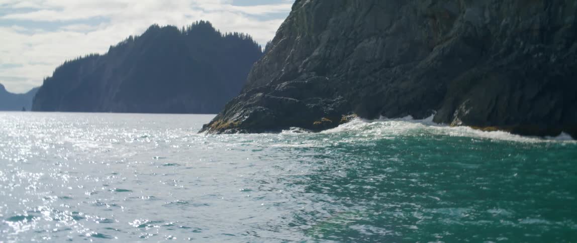 The waves crash against the mountains