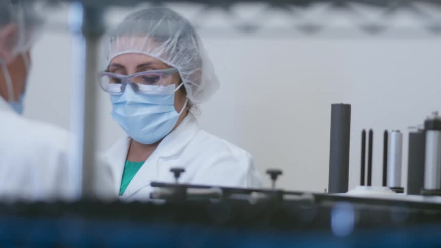 Coworkers wearing protective gear work in laboratory