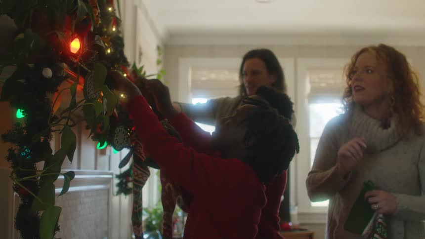 A mom helps her kids hang their stockings on the mantle at christmas