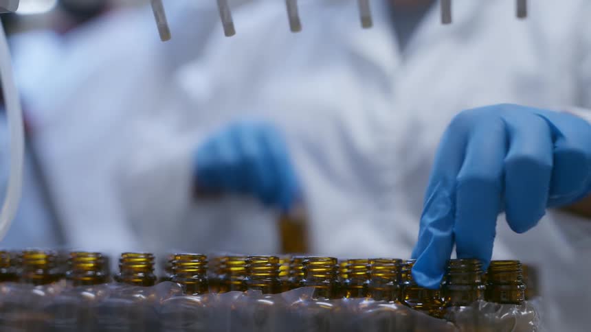 Plant worker replaces filled bottles with unfilled bottles under machine
