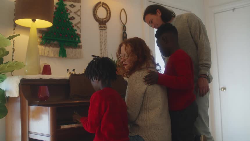 A family watches along as a boy plays the piano at home
