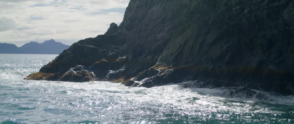 Waves crash against a seaside cliff on a foggy day on a cloudy day