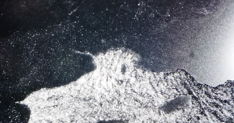 Water bubbles up cracking the surface ice and breaking through