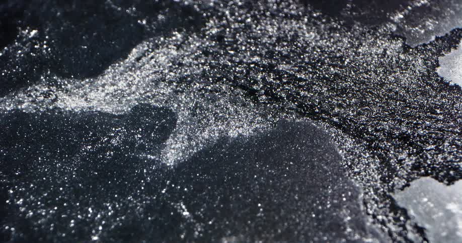 Dark fluid brakes through thin gray sheet and flows across the surface