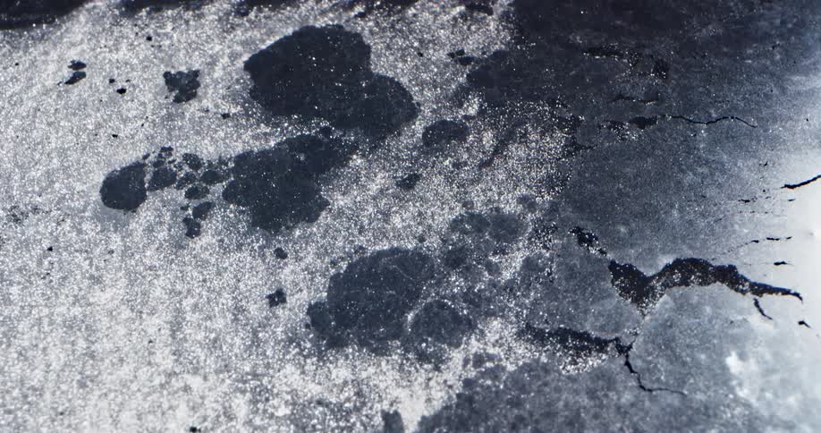 Dark ice sheet reflects sun as flowing melt water pulls chunks off it