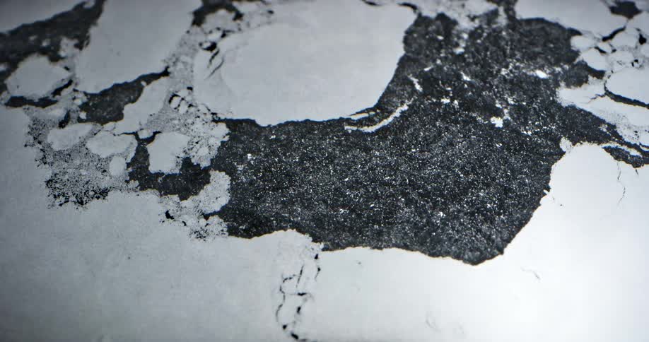 Flowing water pulls white ice sheet apart