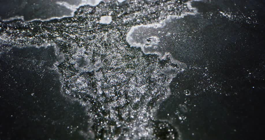 Flowing water breaks through thin sheet of ice
