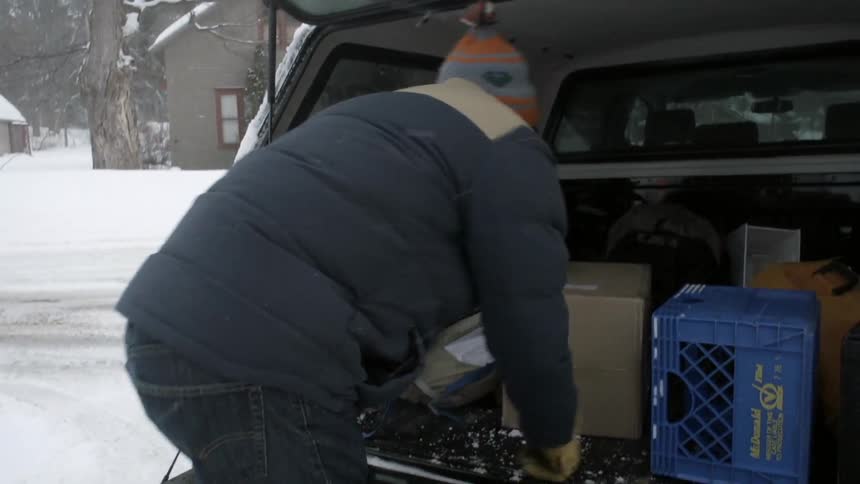 A man lets down his tailgate and climbs in to look for something