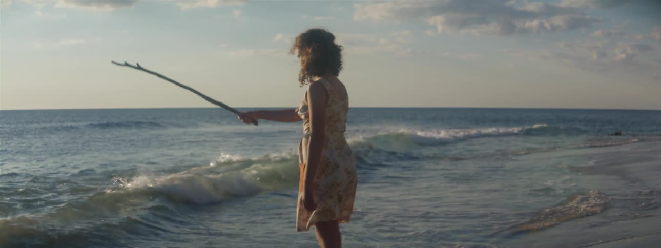 Woman wearing dress kicks at surf and waves stick around