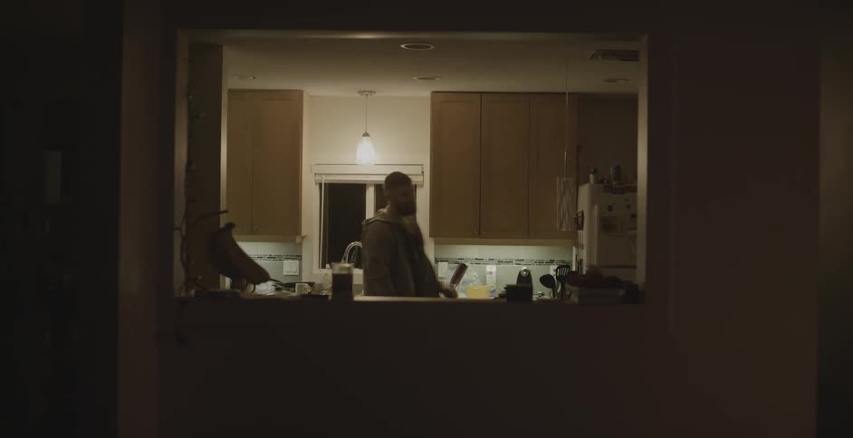 A man walks in to his kitchen and turns the light on and pours himself up cup of coffee