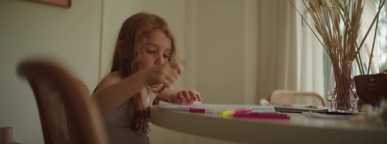 Girl sits at dining table drawing