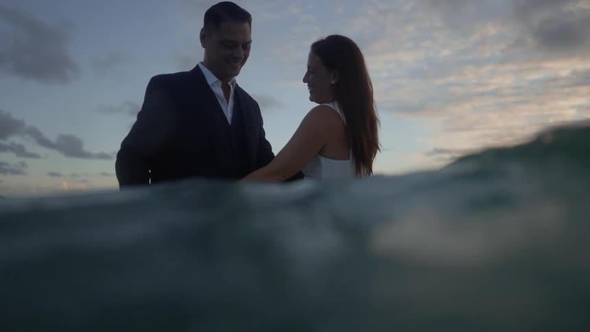 A young couple is in the water and being affectionate with each other