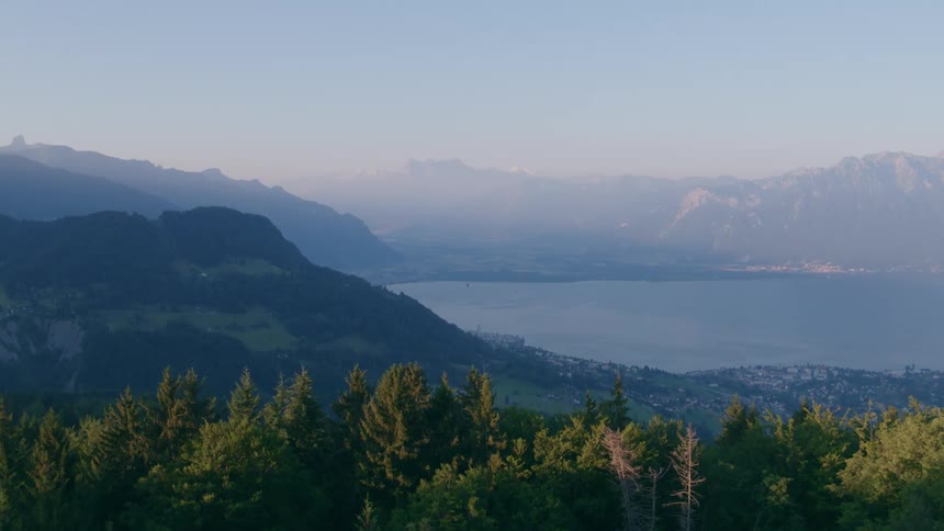 An aerial view of a mountain range and lake with a neighborhood on the shore