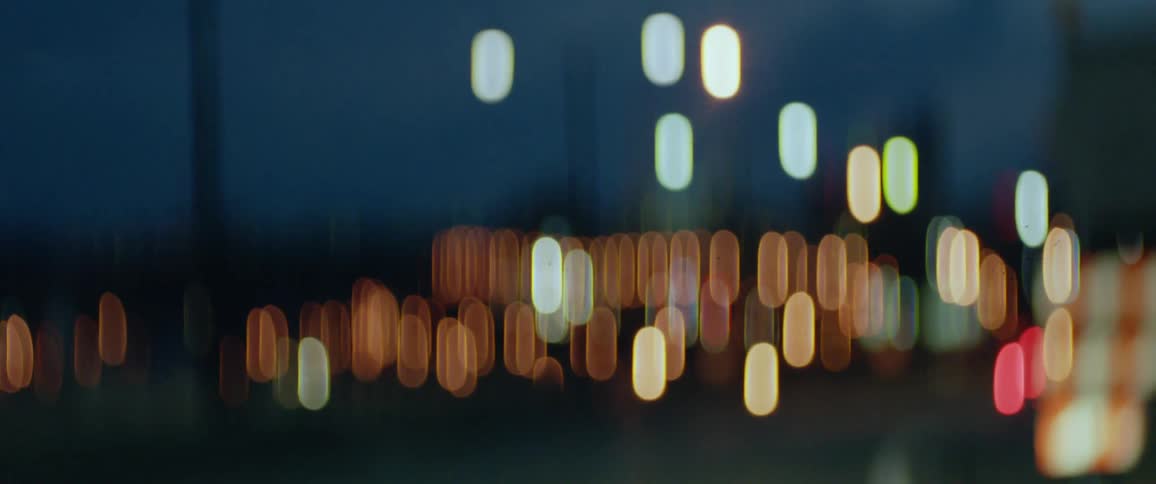Lights are out of focus as silhouettes of buildings stand in the night sky