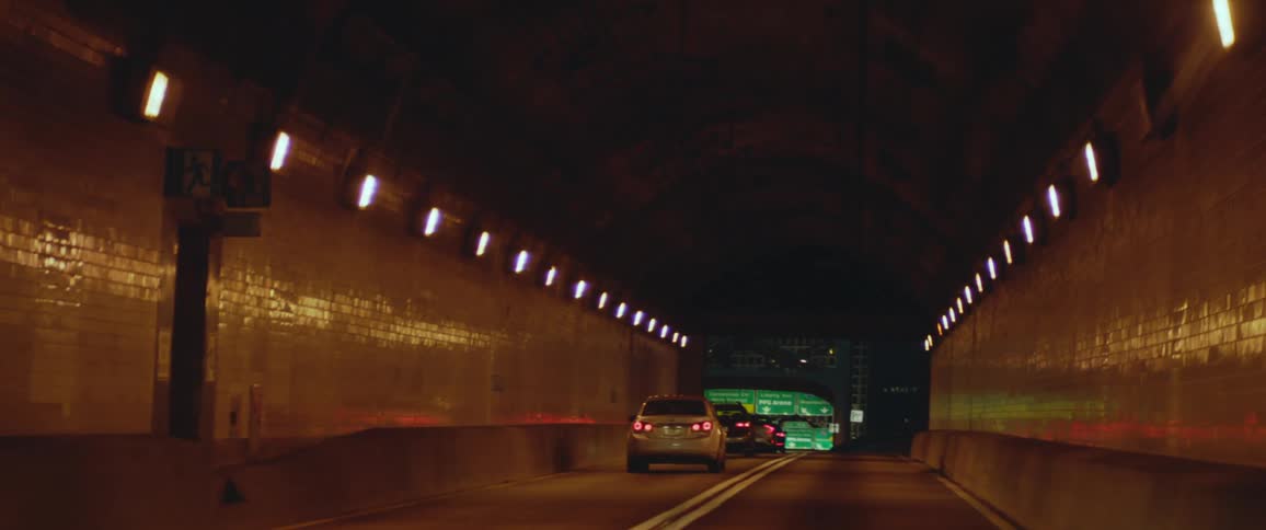 Cars are driving down a tunnel and are on the high way at night time