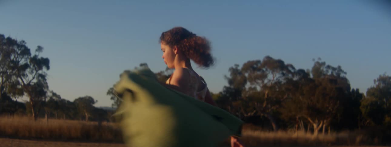 A female wearing a dress is walking and spinning with a jacket