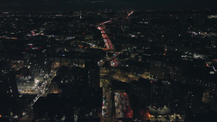Aerial view of vehicles drives on highways and illuminated city buildings at night