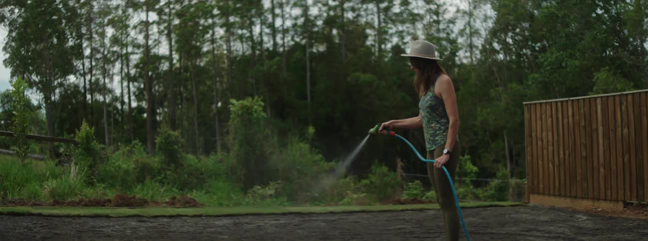 A woman is watering the yard