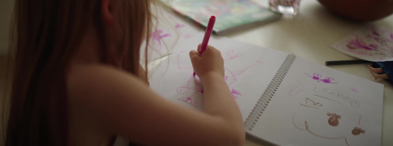 A young toddler is drawing a picture in a note book