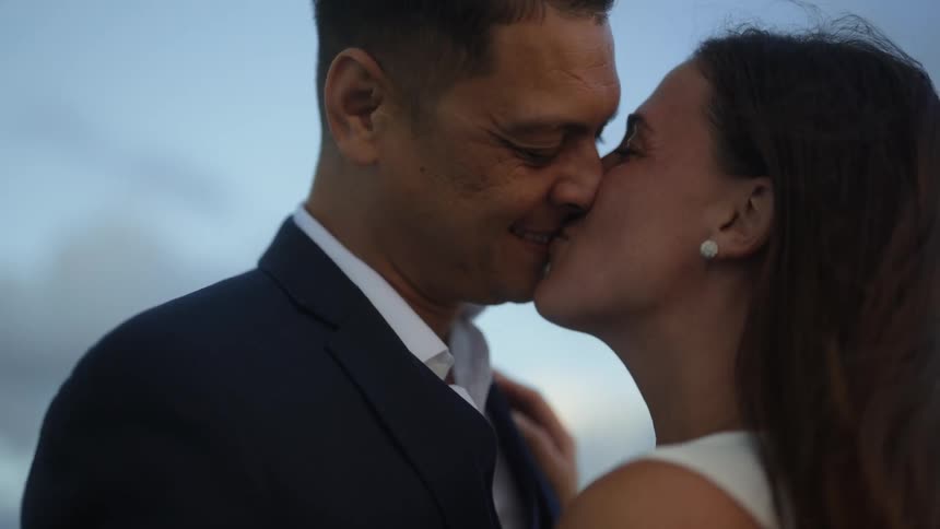 A man and woman share a kiss while standing outdoors during the day