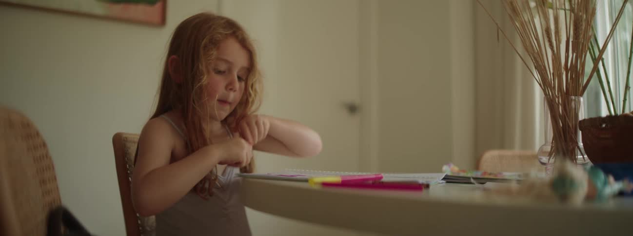Child sitting at dining table draws with markers