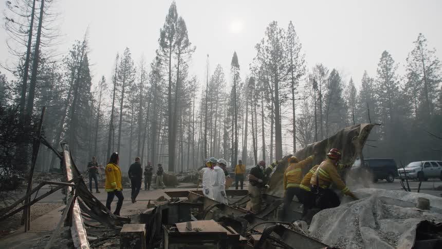 Firefighters clear debris in a fire