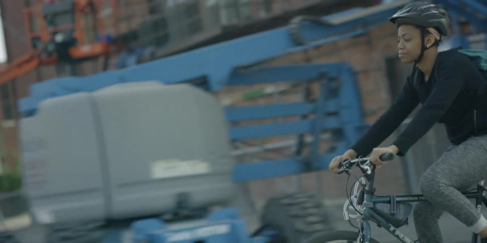 A woman rides a bicycle on a city sidewalk