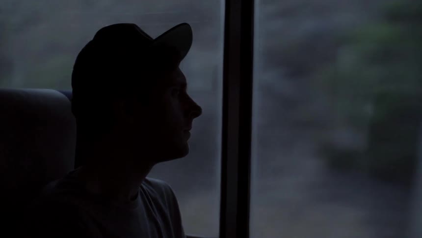 A man sits on a bus while looking out the window