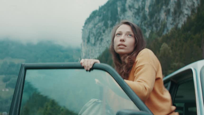 Car stops on highway near mountains and woman gets out with a backpack
