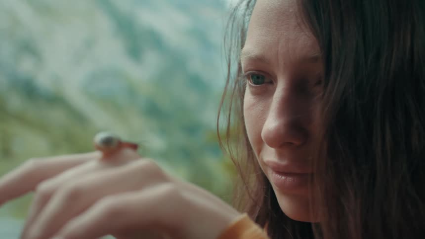 Snail moves on womans hand in the mountain