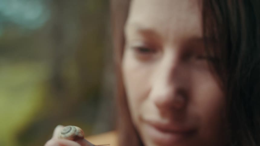 A teenage girl smiles as a snail crawls on her finger