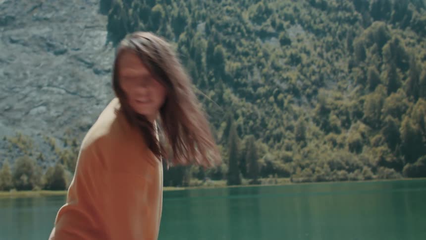A woman throwing her backpack onto a boat and then pushing the boat