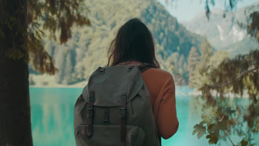 A female removing her backpack near a river