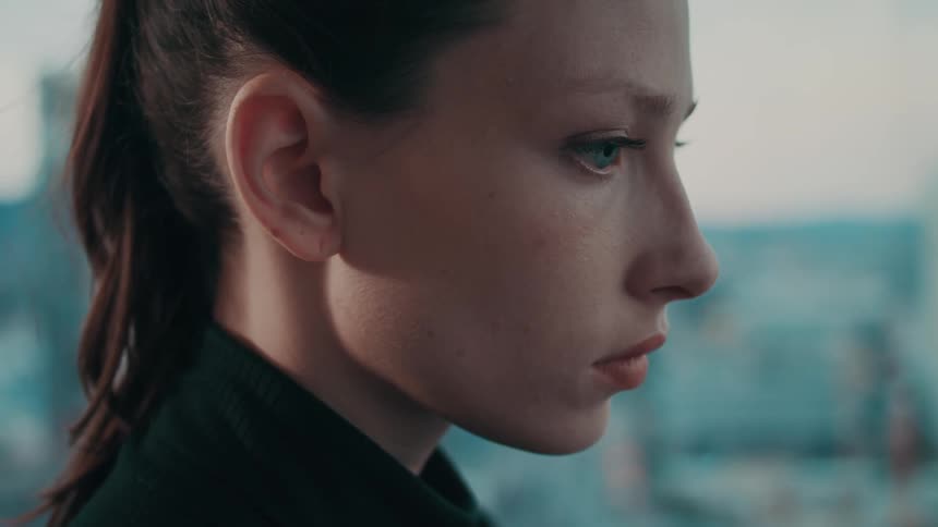 A close up of a women looking out into the distance solemnly