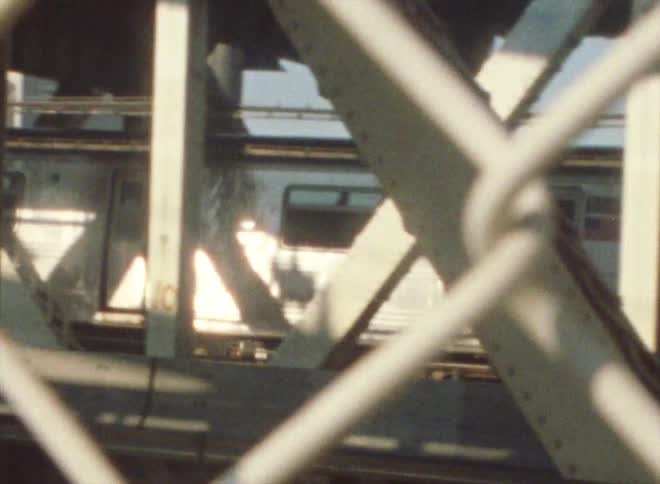 Train runs along a railway track seen from behind the fences