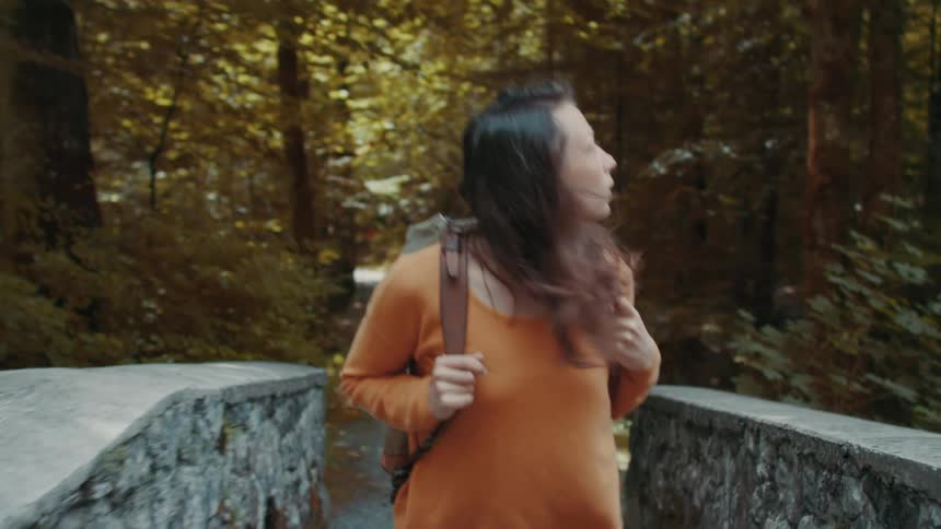 A female walking on a trail bridge in the woods