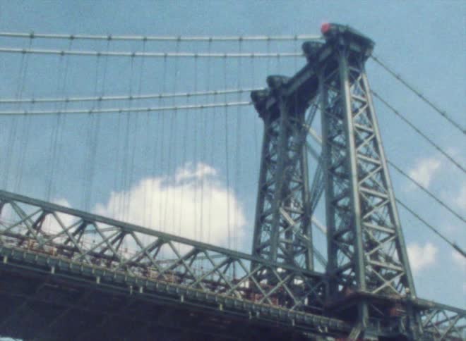 A large bridge over a waterway in a metropolis during the day
