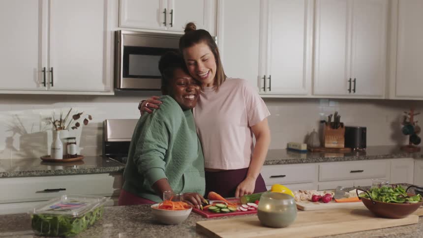 Two women are cooking in the kitchen and hug each other