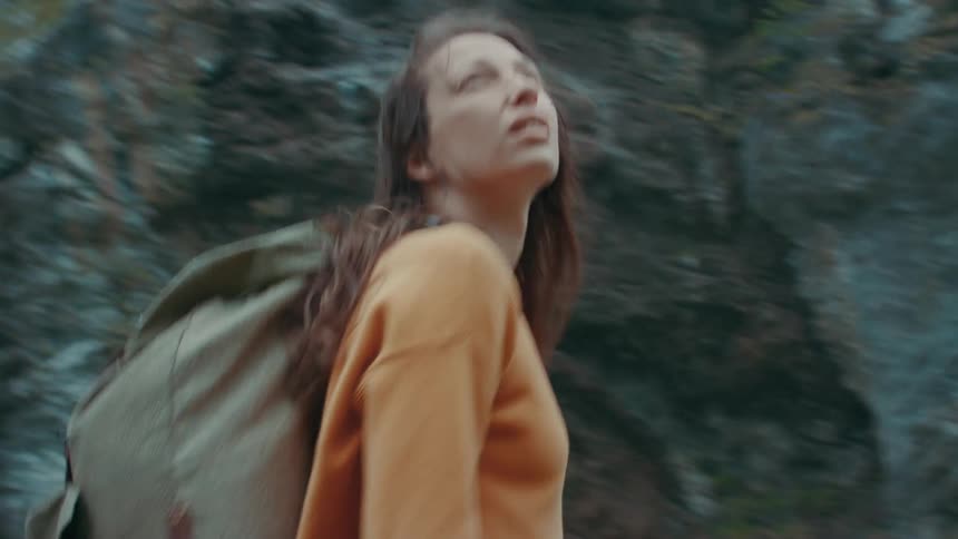 A young woman stands in front of a mountain and spins around taking it all in