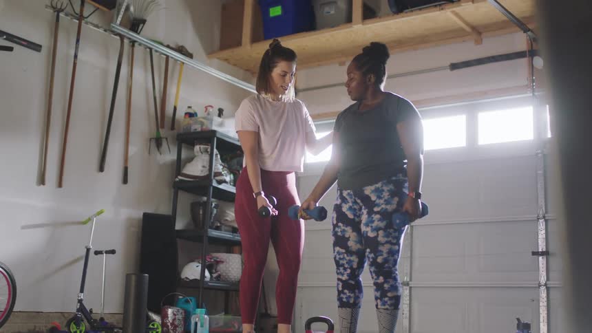 A woman is being coached on lifting weights
