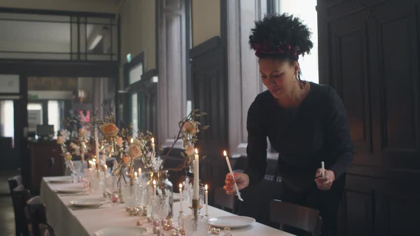 Woman lights candles and places them on dining table in restaurant