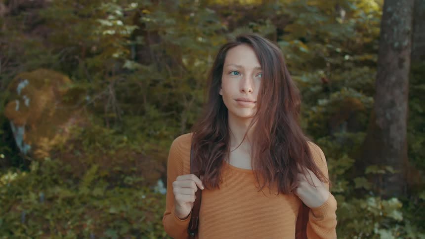 A woman takes off her backpack during a hike in a woods