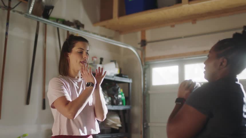 A trainer showing a client how to use weights in a garage