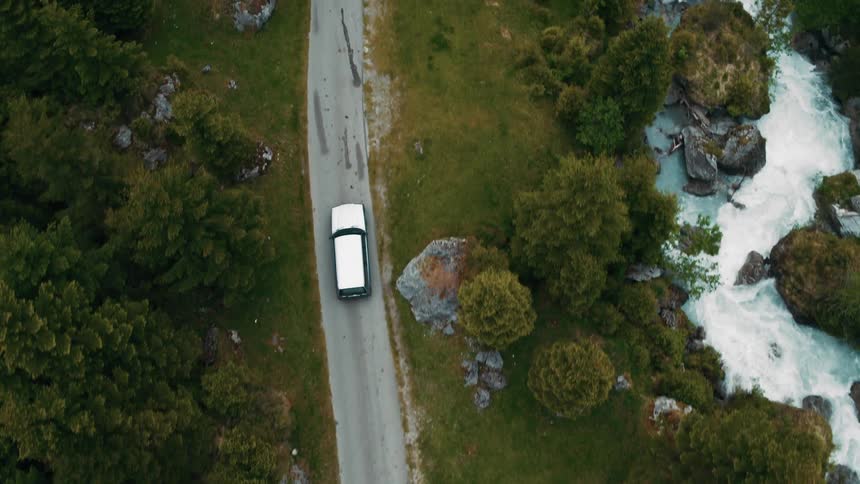 A vehicle drives down a road past a river