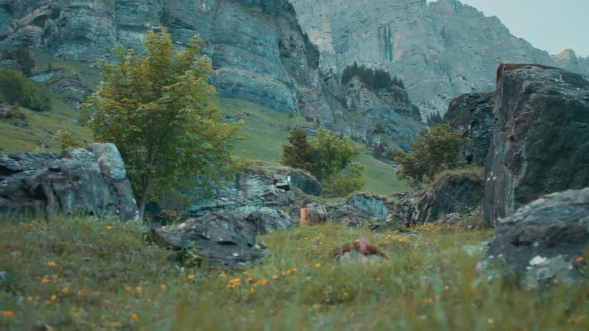 A woman is hiking over the hills towards the mountain