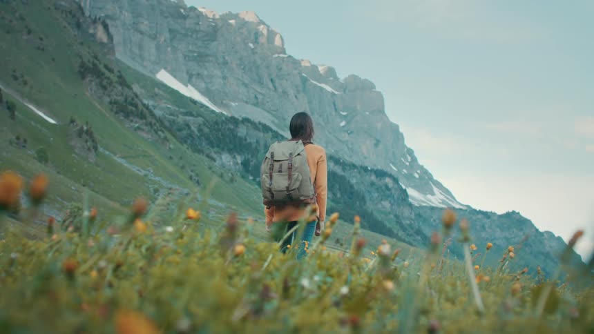 A woman stands before the mountains on a windy day