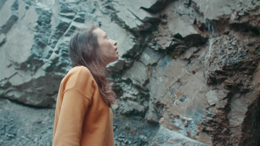 A woman removes her backpack by the waterfall